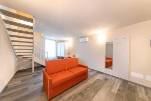 an orange chair in a living room with a staircase at Residenza Cavour - Appartamento D in Tirano