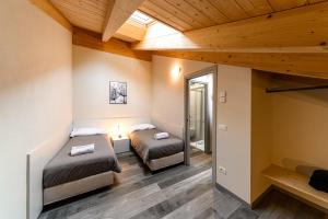 two beds in a room with wooden ceilings at Residenza Cavour - Appartamento D in Tirano