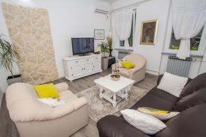 a living room with two couches and a tv at Holiday Home Arboretum in Šibenik