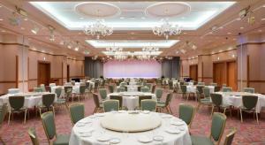 a banquet hall with white tables and chairs and chandeliers at Grand Hotel New Oji in Tomakomai