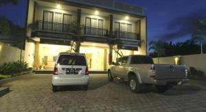 ウブドにあるMANDARI HOTEL SINGARAJAの夜間の家の前に停車した車両2台