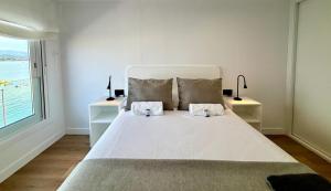 a bedroom with a large white bed with two night stands at Holibai, Meiga Do Mar, Apto moderno, vistas al mar y playa cerca, Baiona in Baiona