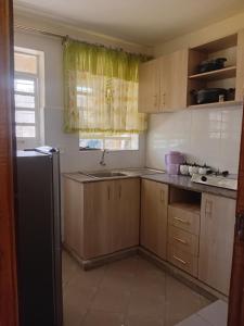 a small kitchen with wooden cabinets and a refrigerator at Jeff HOMES Bnb in Nakuru +14 photos