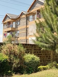 a building with a balcony and a palm tree at Jeff HOMES Bnb in Nakuru