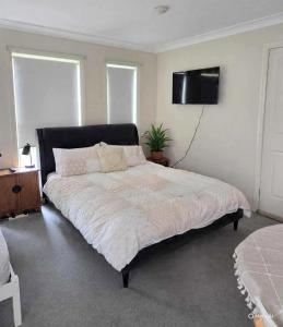 a bedroom with a large bed with a television on the wall at The Studio on Ashtree in Armidale
