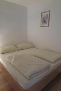 a bed with white sheets and a picture on the wall at Apartment Omerovic in Novalja