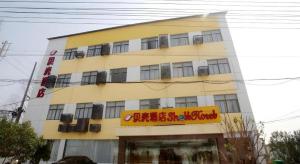 un edificio giallo con un cartello davanti di Shell Nanjing City Qixia District Baguazhou Hotel a Nanjing
