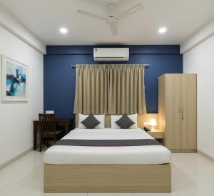 a bedroom with a bed with a blue wall at Premiere Suites - Brookfield in Bengaluru