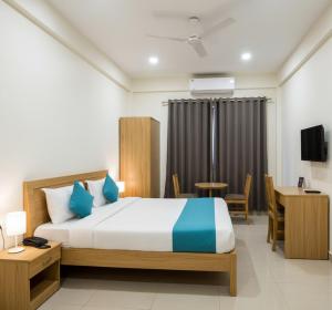 a hotel room with a bed and a table and chairs at Premiere Suites - Brookfield in Bengaluru