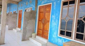 a blue building with a wooden door and windows at Hotel O Puri Azzura Danau Ranau Near Danau Ranau Pusri in Jepara