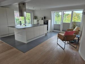 una cucina con mobili bianchi, tavolo e sedie di Sunny Flensbo Apartment a Flensburgo