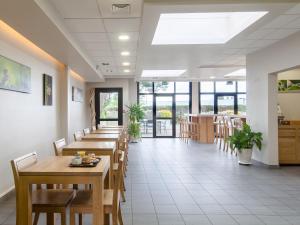 a restaurant with wooden tables and chairs and windows at B&B HOTEL Paris Nord Aulnay-sous-Bois in Aulnay-sous-Bois