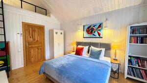 a bedroom with a blue bed and a book shelf at Dom w Starym Sadzie z basenem i sauną - Beskid Wyspowy in Nowe Rybie