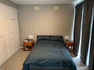 a bedroom with a bed and two tables and a window at Sunset View House in Warburton
