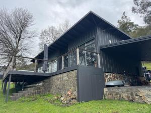 a black house with a stone wall at Sunset View House in Warburton