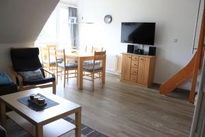 a living room with a table and a television at Ferienwohnung mit Seeblick und Schwimmbadnutzung in Cuxhaven in Cuxhaven