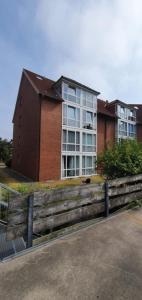 a building with a wooden fence in front of it at Ferienwohnung mit Seeblick und Schwimmbadnutzung in Cuxhaven in Cuxhaven