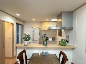 a kitchen with a table with chairs and a refrigerator at 貸切 2部屋5名可能 駅近い徒歩6分 秋葉原 新宿 鎌倉へ直通 スカイツリー ディズニーランド近く 悠悠之家 in Tokyo