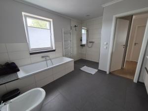 un bagno con vasca, lavandino e finestra di Sunny Flensbo Apartment a Flensburgo Altre 14 foto