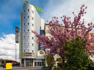 un hotel con un árbol de flores frente a un edificio en B&B HOTEL Paris Est Bondy, en Bondy