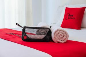 Una habitación de hotel con una cama roja con una toalla y una bolsa. en RedDoorz near Puskesmas Sei Jang Tanjung Pinang, en Tanjung Pinang