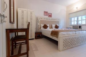 a bedroom with a bed and a table and a chair at AV apartment beach candolim in Aguada +16 photos