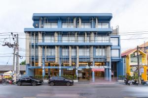 a blue building with cars parked in front of it at Wachi Hotel in Songkhla