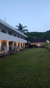 a large building with a grass field in front of it at Bale Hotel & Cowork in Kuta Lombok