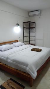 una camera da letto con un letto grande con lenzuola bianche di Bale Hotel & Cowork a Kuta Lombok 1 altra foto