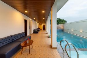 a pool with a couch and a table next to a pool at The Colonial - A Lake View Hotel in Udaipur in Udaipur