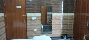Un baño con pared de madera, espejo y inodoro. en Mannat Residency Hotel, en Noida