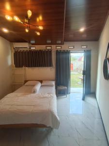a bedroom with a bed and a large window at Satera Homestay in Seteluk