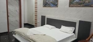 1 cama con sábanas blancas y almohadas junto a la chimenea en Mannat Residency Hotel, en Noida