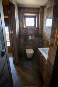 a bathroom with a toilet and a sink and a window at Bārtas in Kaijciems