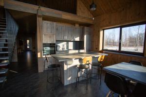 a kitchen with a counter and stools in a cabin at Bārtas in Kaijciems