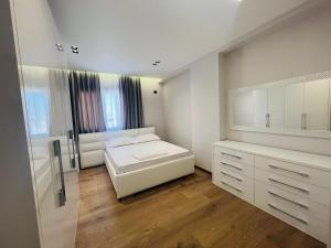 a white bedroom with a bed and a mirror at Sea view apartament in Durrës