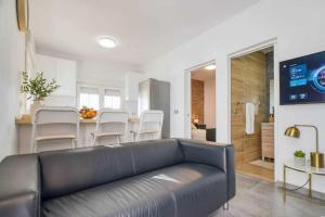 un salon avec un canapé noir et une cuisine dans l'établissement Sun-Kissed Villa with Private Heated Pool & BBQ, à Las Medianias