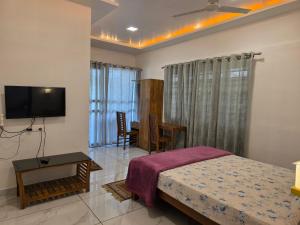 a bedroom with a bed and a table and a television at BEN COTTAGE in Thekkady