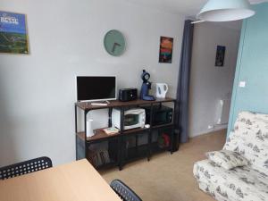 ein Wohnzimmer mit einem TV und einem Tisch mit einer Mikrowelle in der Unterkunft Appt 4 prs Tour de La Biche depart skis aux pieds in Besse-et-Saint-Anastaise