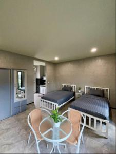 two beds in a room with a table and chairs at Dee Dee Apartments ChumPhae in Chum Phae