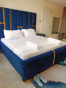 una cama con cabecero azul y un par de zapatillas en Murangiri Accommodations, en Mombasa