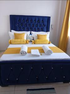 Una gran cama azul con dos toallas. en Murangiri Accommodations, en Mombasa