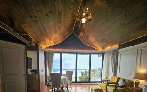 a living room with a wooden ceiling and a large window at THE ENGLISH COTTAGE in Darjeeling