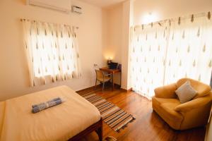 a room with a bed and a chair and a desk at Odd Table-Social Homestay in Mandrem