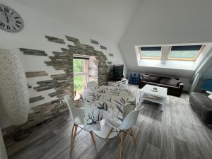 a living room with a table and chairs and a clock at Le petit Kichon in Gérardmer