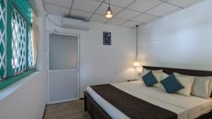 a bedroom with a bed with blue pillows and a window at Villa Coleus in Tangalle