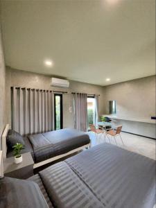 a bedroom with two beds and a table and chairs at Dee Dee Apartments ChumPhae in Chum Phae