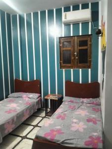 two beds in a room with blue and white stripes at Safy Guest House in Jazīrat Aswān