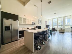 a kitchen with a refrigerator and a counter with stools at Stylish 2BR Loft with Top-Tier Amenities - 104 - GL in Glendale
