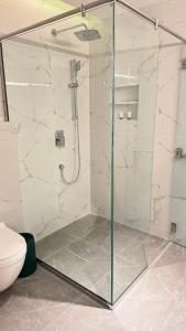 a glass shower in a bathroom with a toilet at Amaris Hotel in Al Ḩamrāʼ